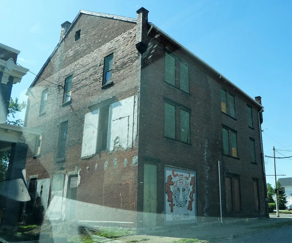 Ancien bâtiment de briques aux fenêtres condamnées et à la façade peinte.