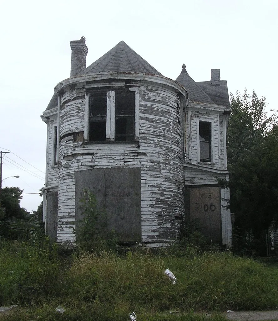 Wooden house with a turret and boarded openings.