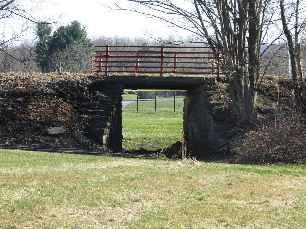 Ancien pont ferroviaire en pierre avec garde-corps rouge à Oneida.