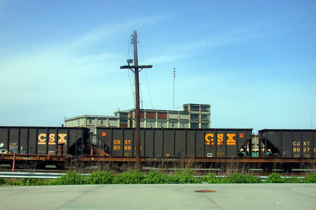 Old industrial building with boarded openings behind freight wagons.