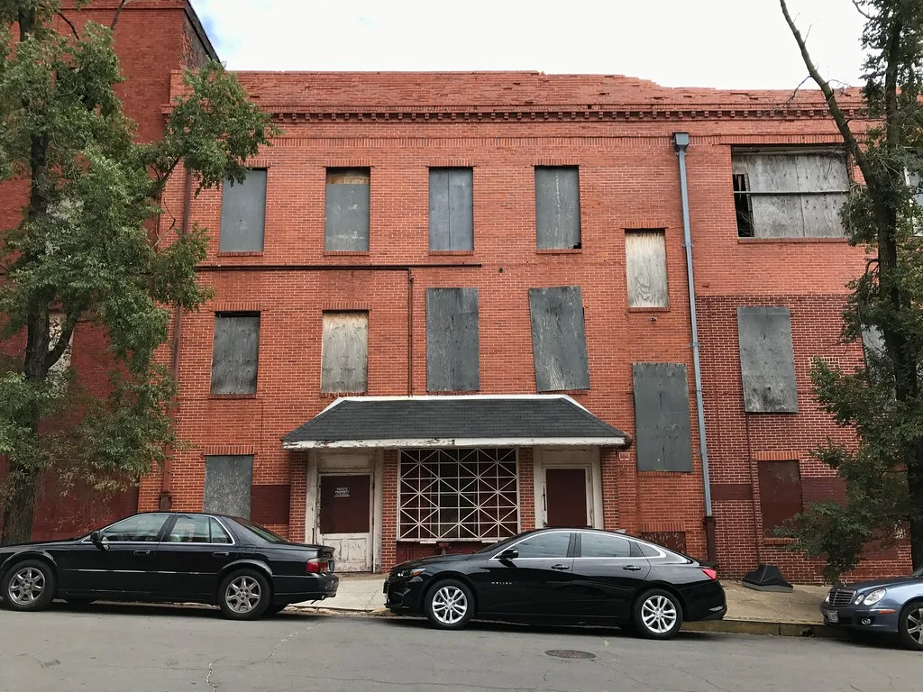 Brick building with boarded windows and entrances.