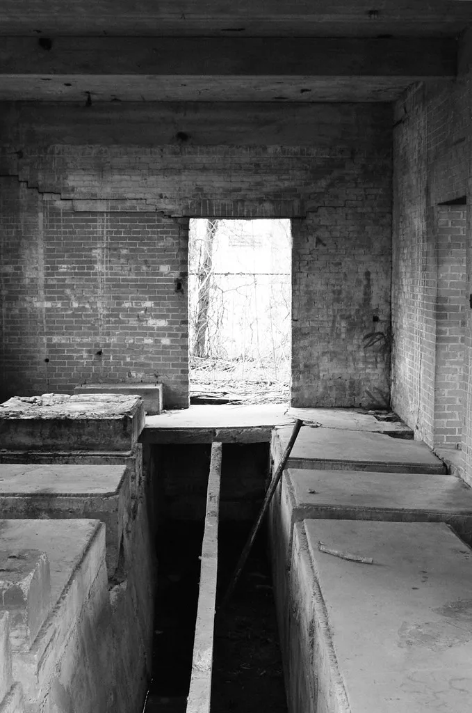 Ancien intérieur de briques avec fosses ouvertes et murs fissurés.