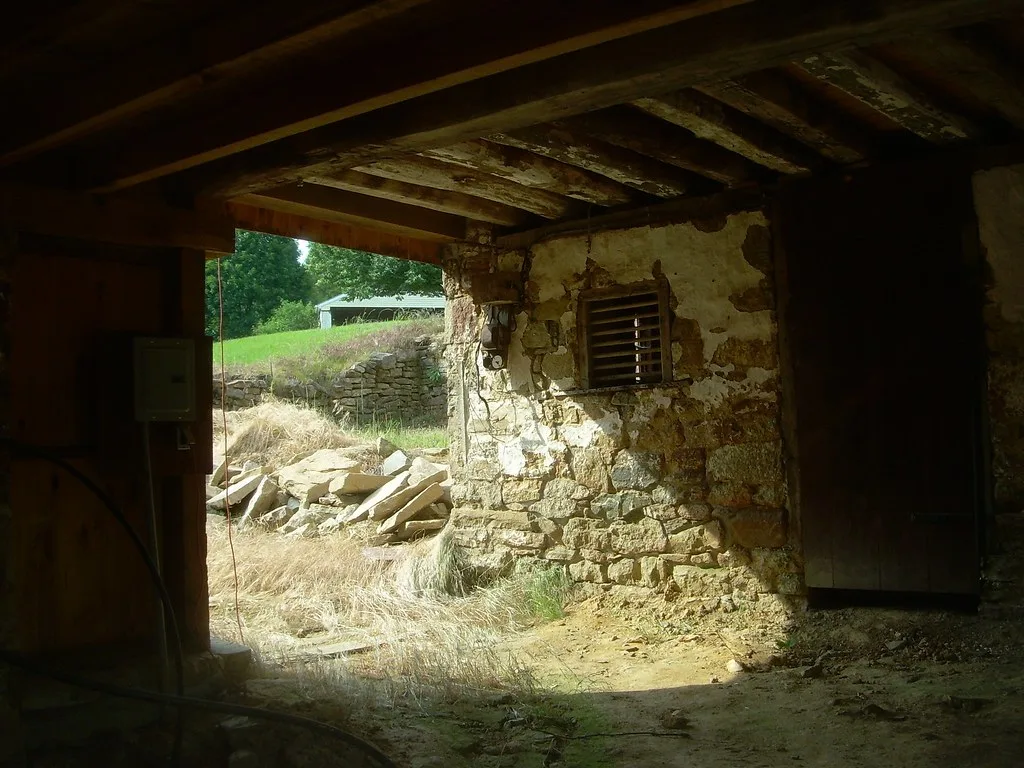 Interior of an old stone barn opening onto grassy ground.