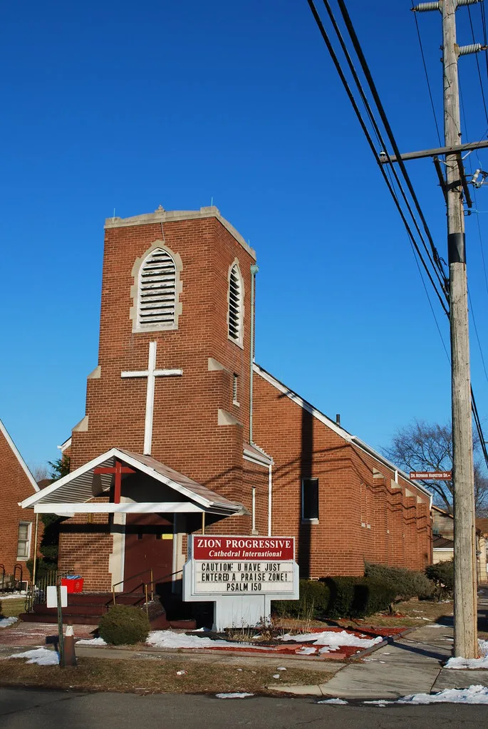 Église en brique à Gary avec clocher carré et grande croix blanche.