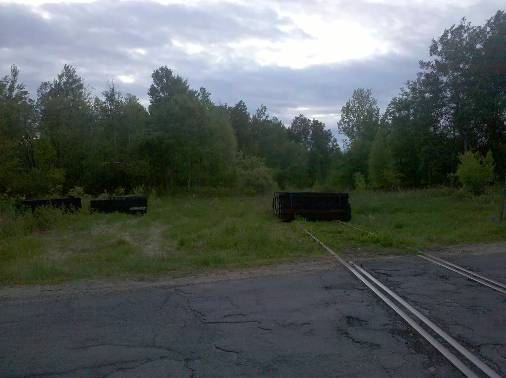 Old railway tracks overgrown with grass and blocked by stacked sleepers.