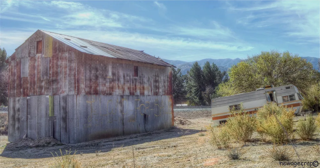 Old rusty metal shed beside a neglected caravan.