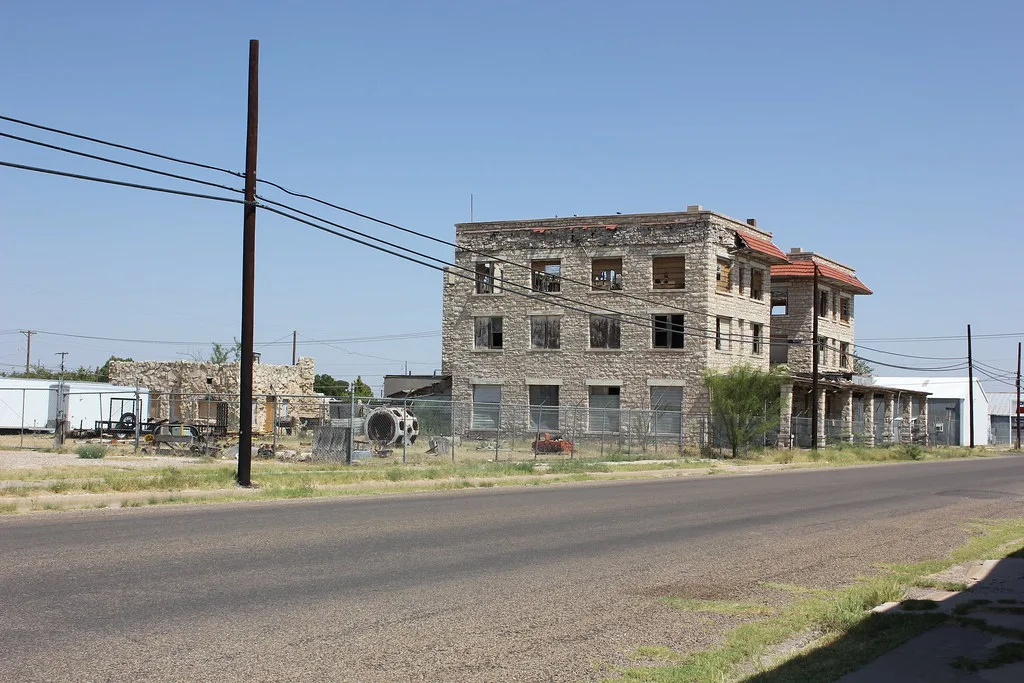 Old stone building with empty windows behind a fence.