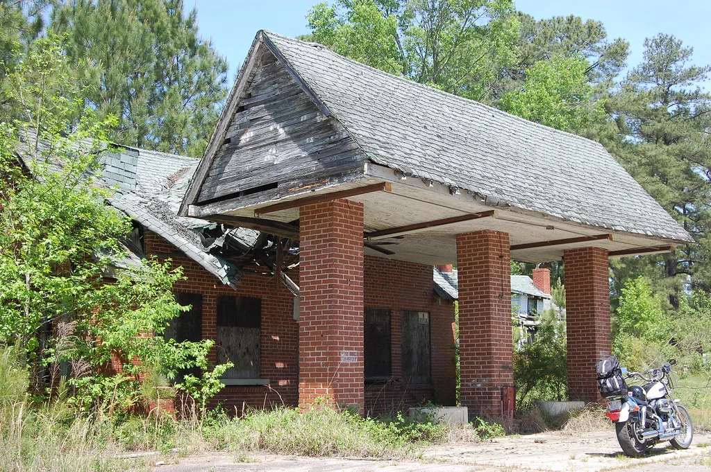 Old brick building with a collapsed roof behind a motorcycle.