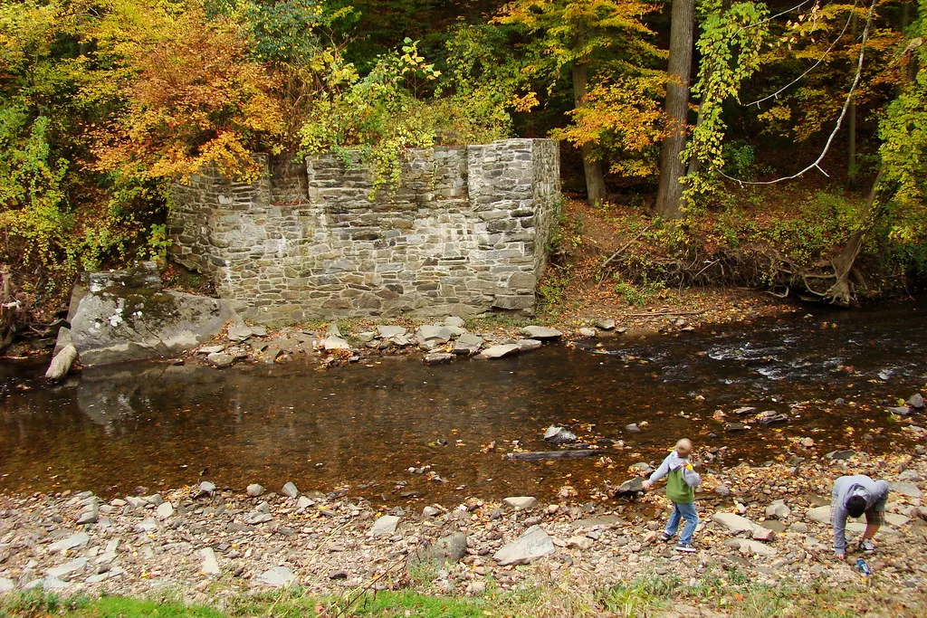 Old stone abutment beside a stream in autumn.