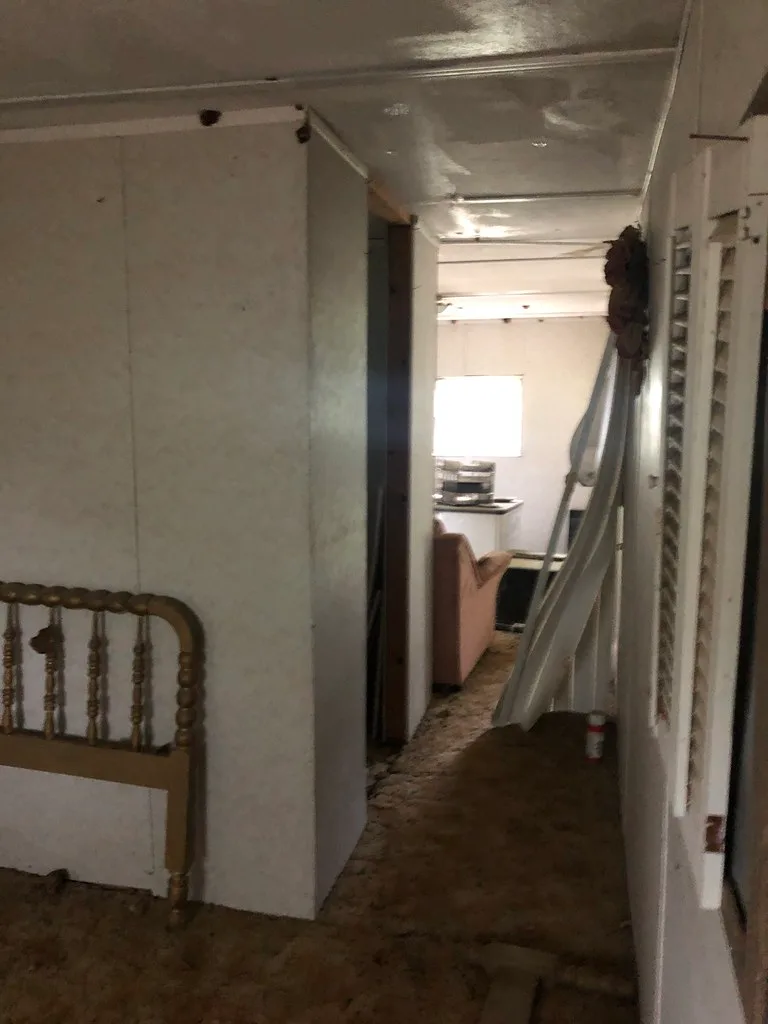 Old interior with a damaged partition and debris on the floor.