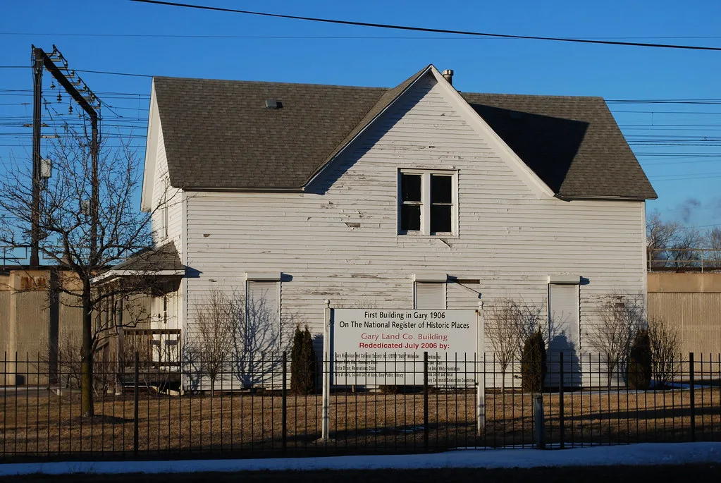 Old white Gary Land Company building with boarded windows.