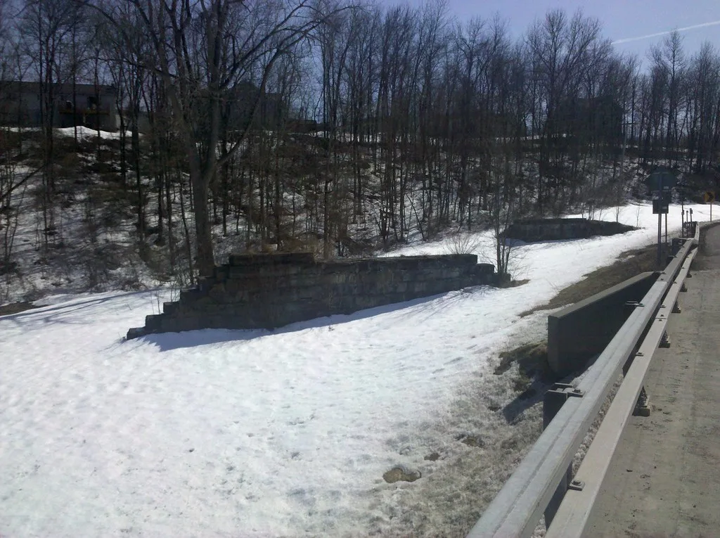 Vestiges de maçonnerie en pierre dans la neige au bord d’une route.
