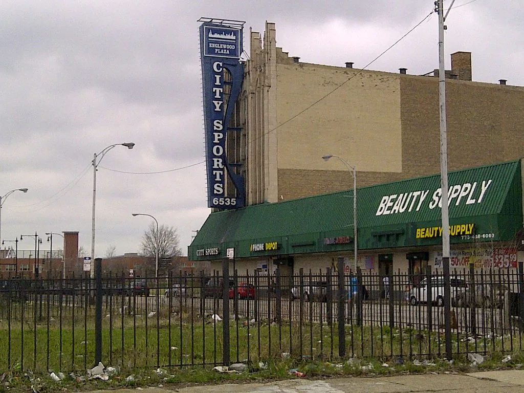 Ancien bâtiment commercial sur Halsted Street à Chicago, derrière un terrain vacant clôturé.