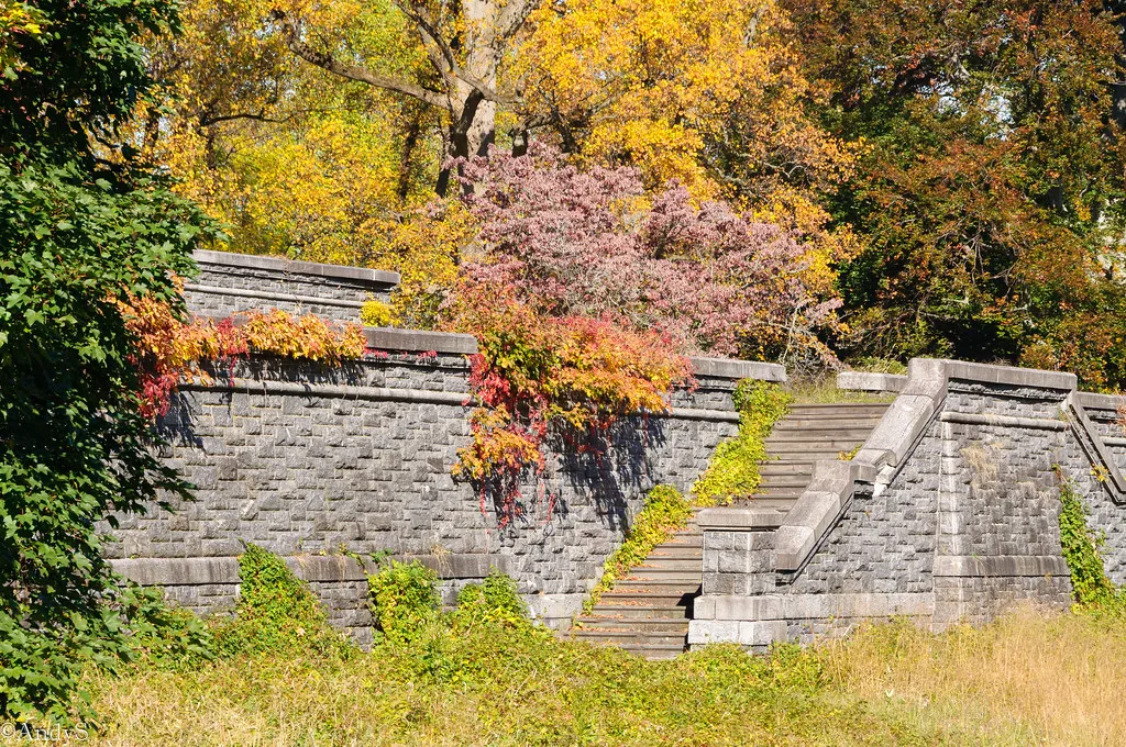 Old stone walls and staircase bordered by autumn foliage.