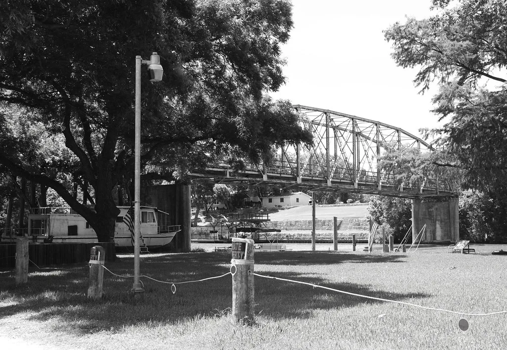 Former steel truss bridge over the Guadalupe River in Seguin, in black and white.