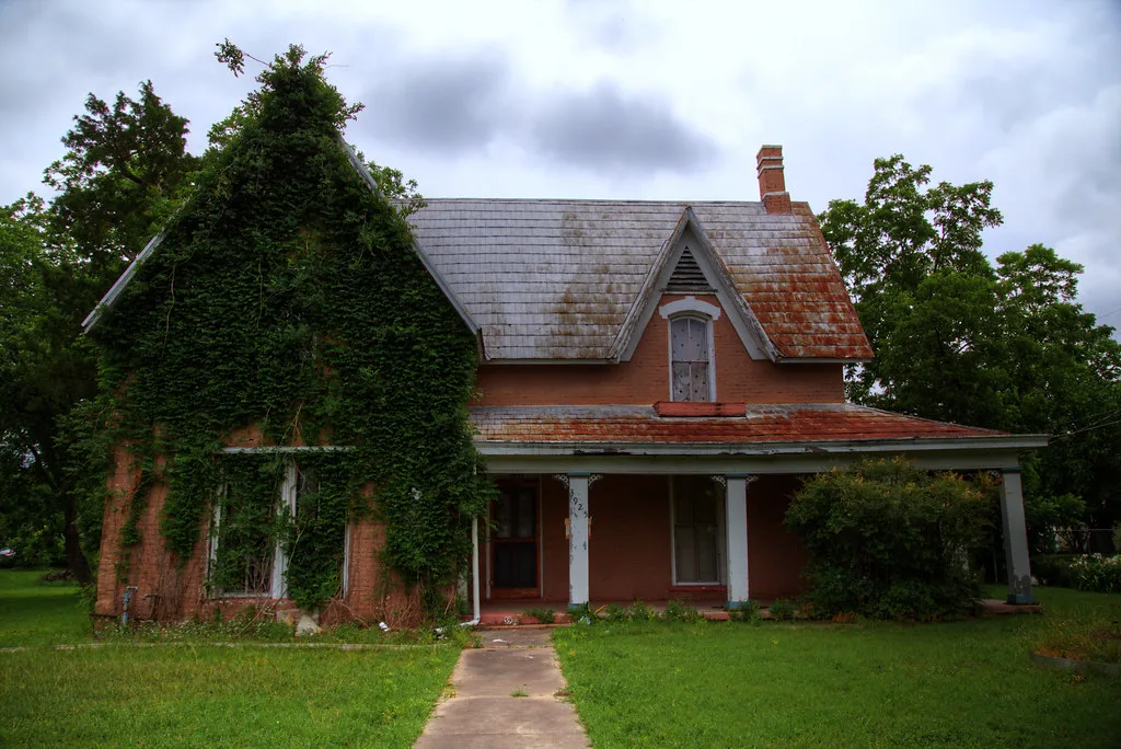 Ancienne maison de briques dont un pignon est couvert de lierre.