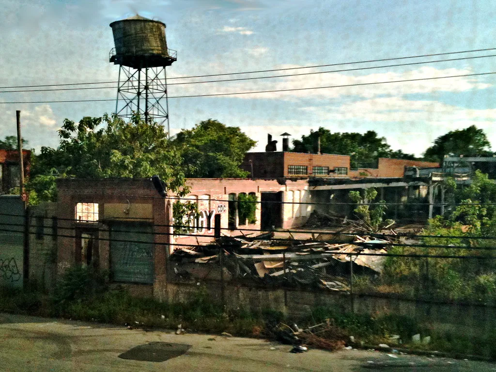 Old industrial site with collapsed roofs beneath a water tower.