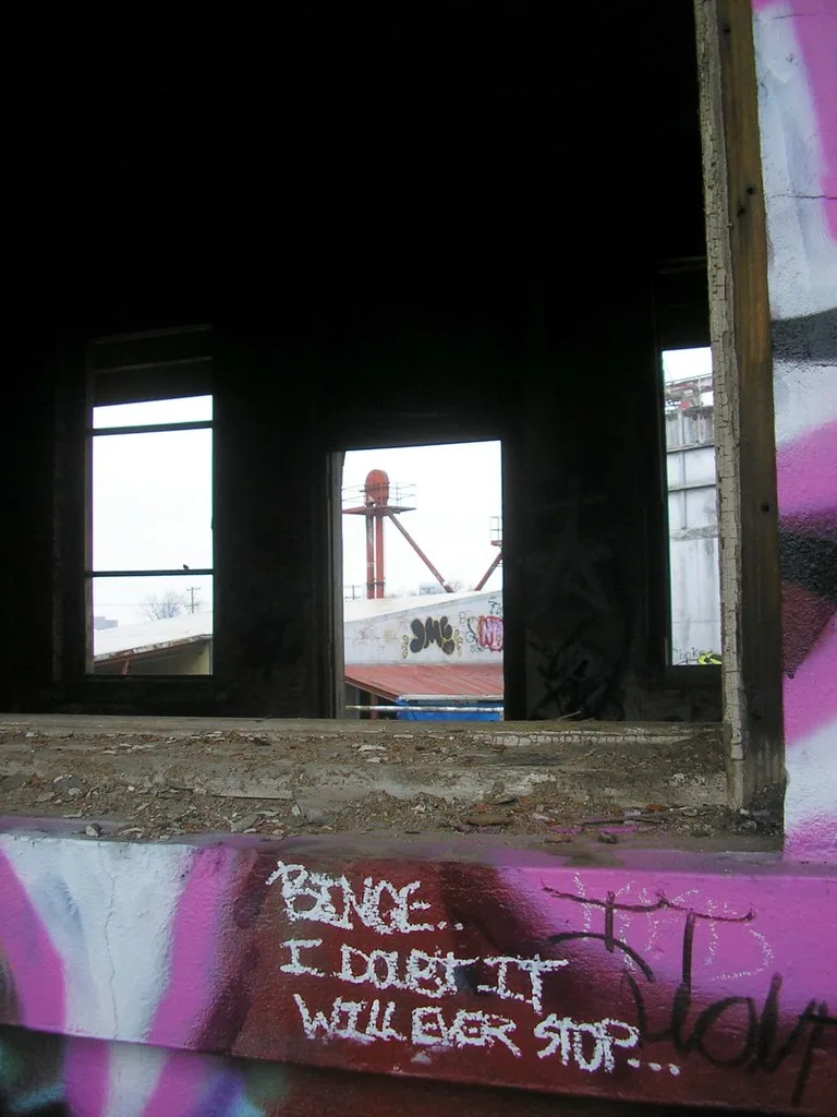 Ouvertures vides d’un bâtiment industriel aux murs couverts de graffitis.