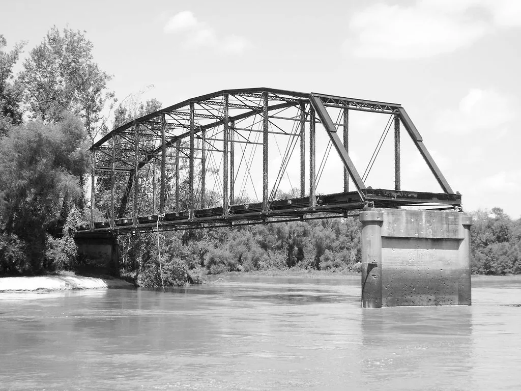 Ancienne travée métallique sur des piles au-dessus d’une rivière.