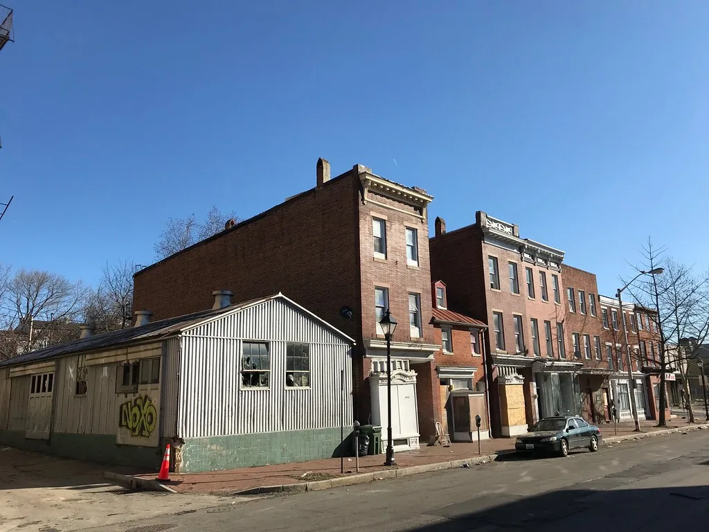 Old brick facades and an annex with broken windows on a street.