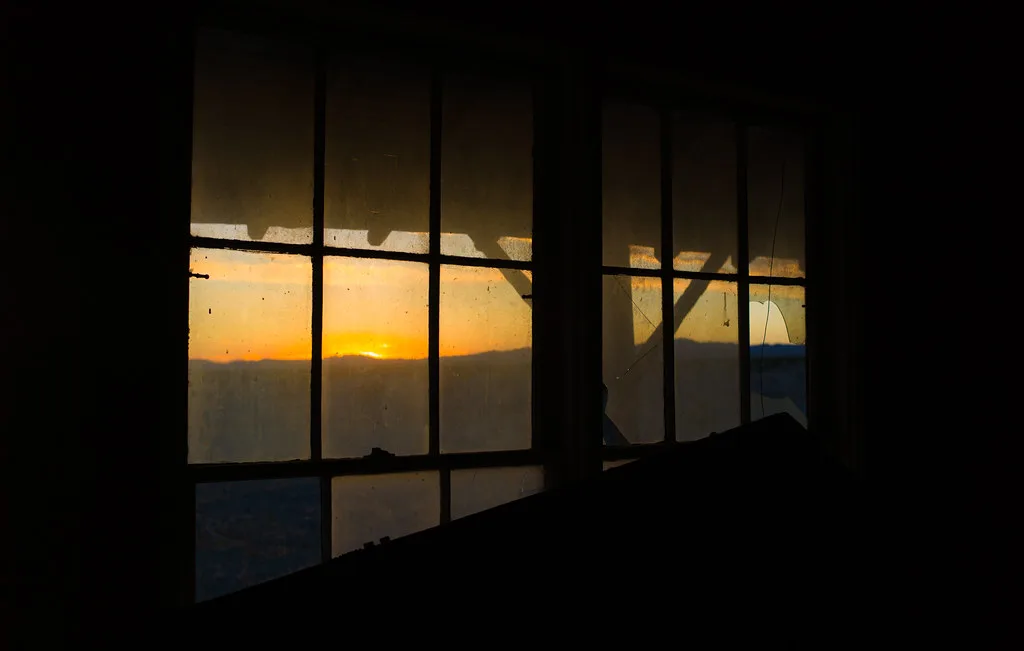 Setting sun through the broken panes of an old window.