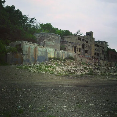 Gutted industrial buildings behind a heap of masonry and rubble.