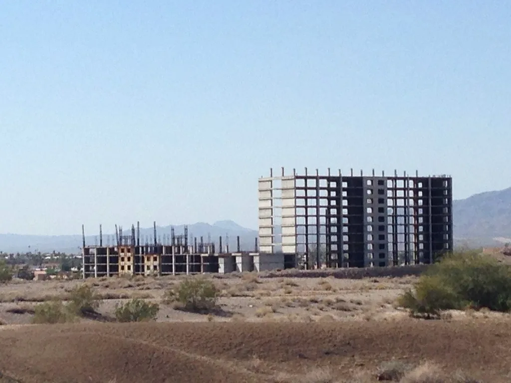 Bare frame of an unfinished building on dry land.