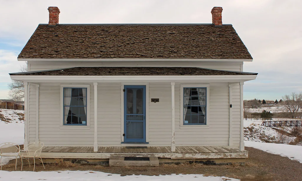 White facade of Gully Homestead in the snow, with its porch and blue door.