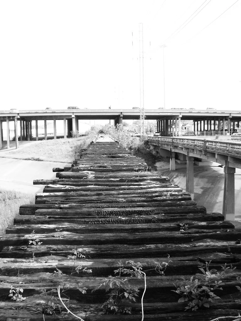 Traverses disjointes d’un pont ferroviaire abandonné sans rails près de viaducs routiers.