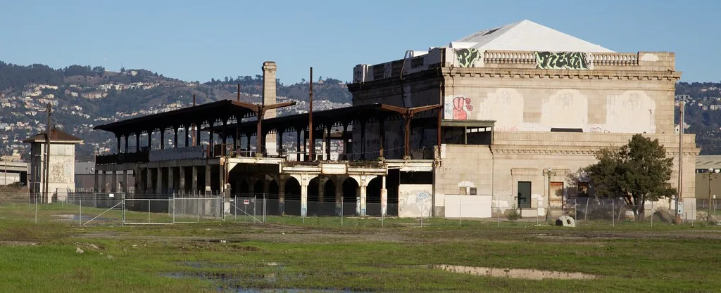 Ancienne gare fermée avec quais sur deux niveaux et structures métalliques rouillées.