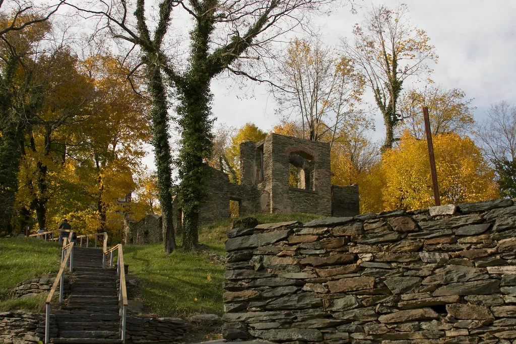 Stone ruins on a wooded slope above a staircase.