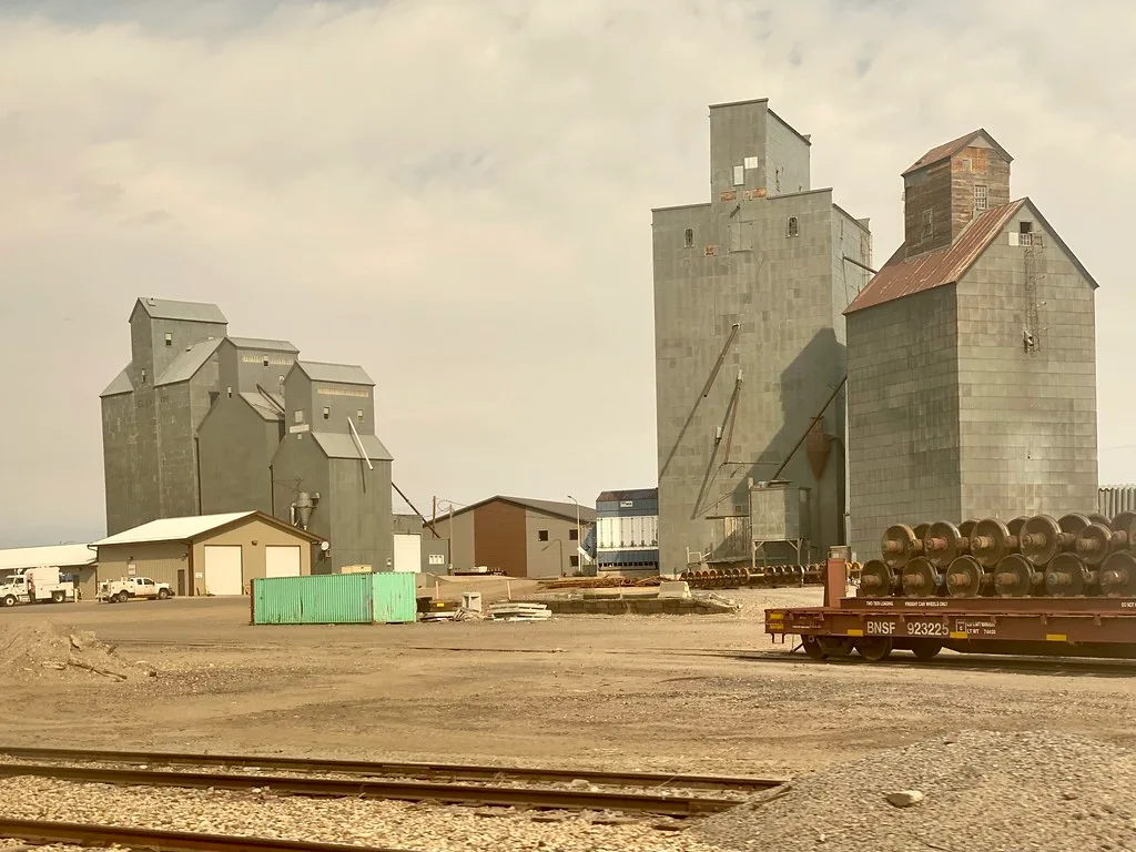 Grain elevators in Williston with tracks and a freight car in the foreground.