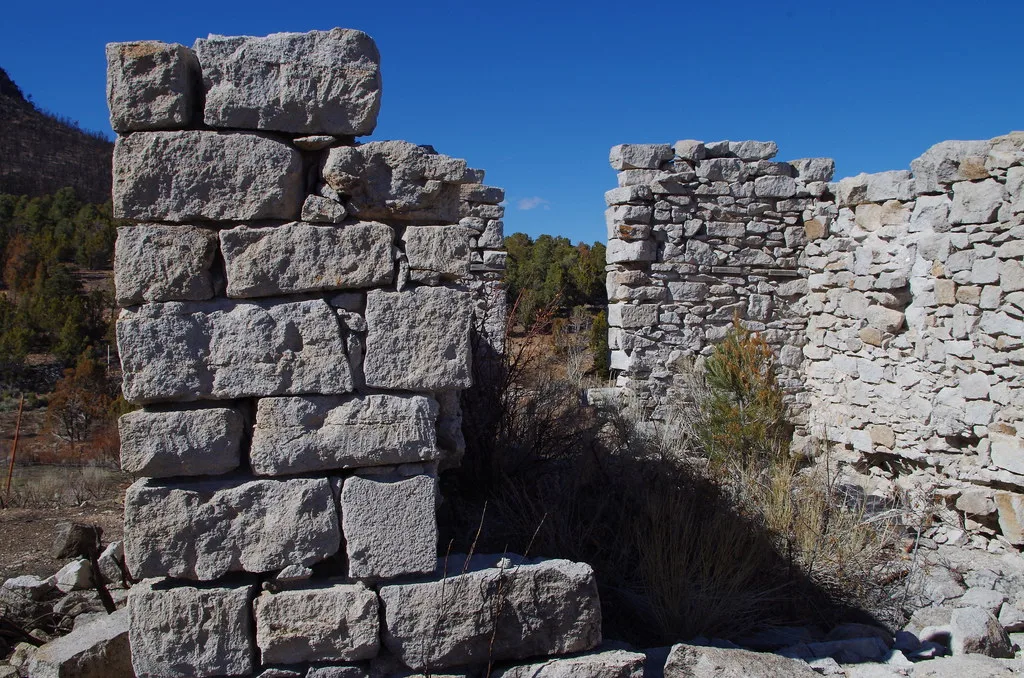 Incomplete walls of a stone ruin under a blue sky.