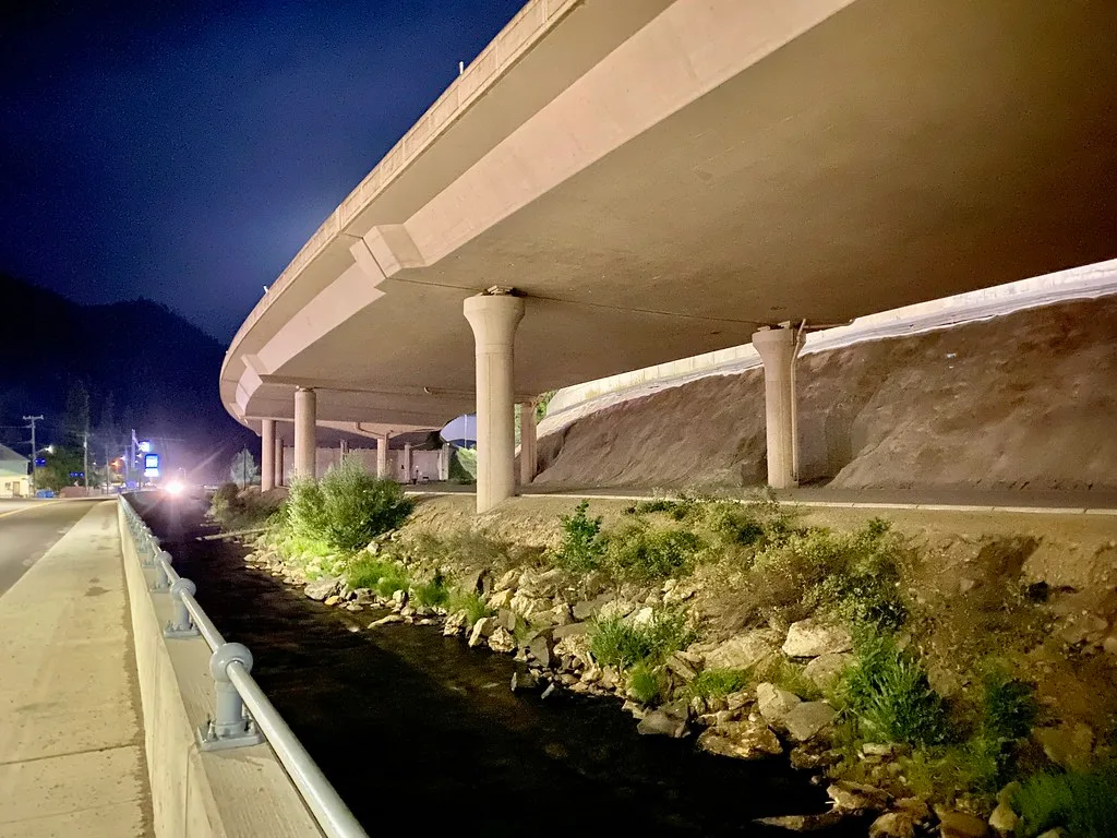 Interstate 90 viaduct in Wallace illuminated at night above the waterway.