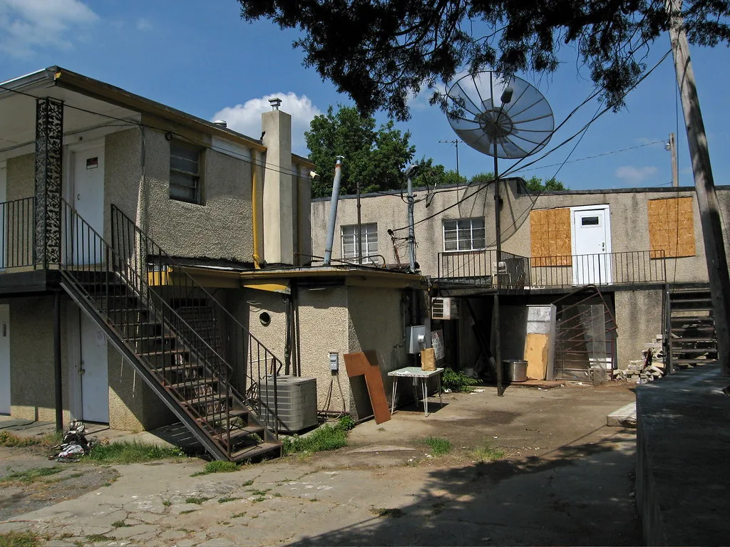 Courtyard of an old lodging building with partly boarded openings.