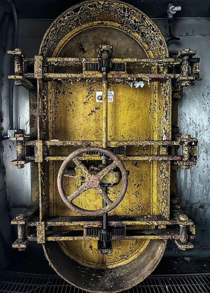 Corroded old yellow industrial door with a metal handwheel.