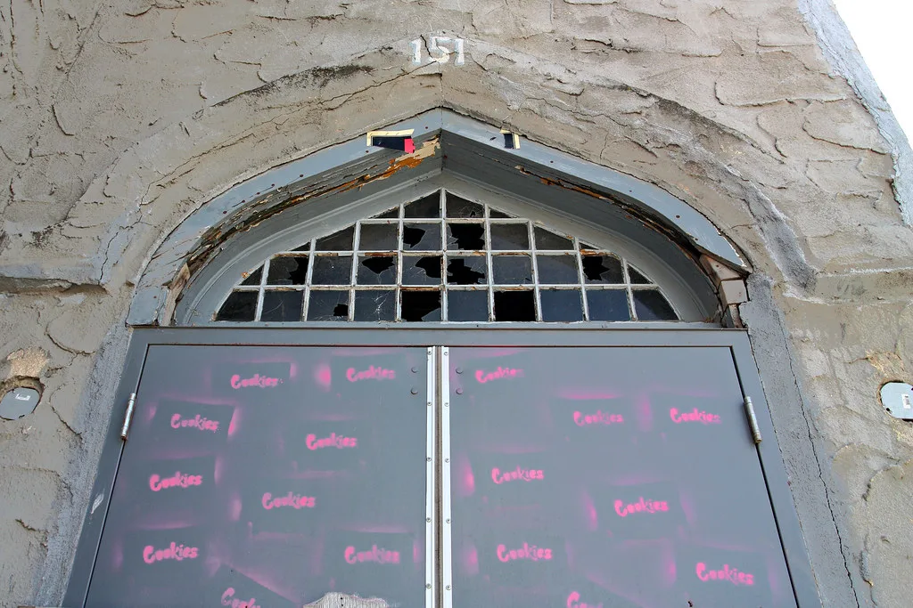 Sealed arched entrance topped with broken panes in a stone wall.
