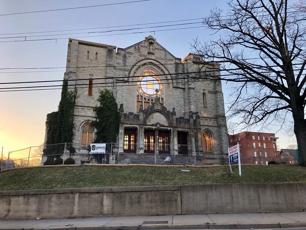Ruined former church with an empty rose window and an ivy-covered facade behind fencing.