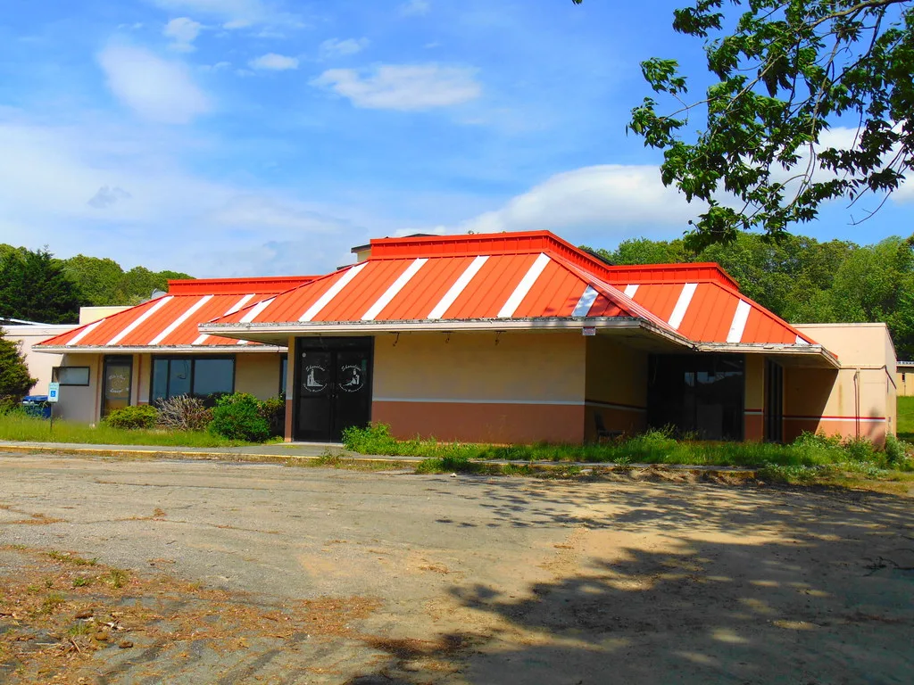 Closed former restaurant with a red roof beside an empty parking lot.