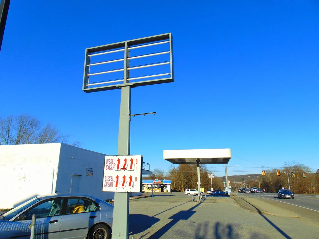 Former gas station with an empty canopy and bare sign frame.