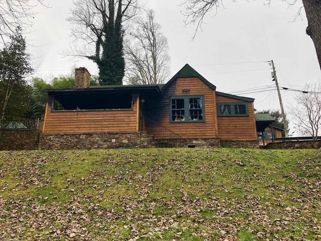 Small wooden house with broken windows and an open porch.