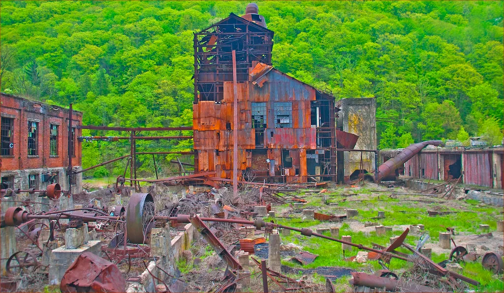Ancien site industriel aux bâtiments éventrés et aux machines rouillées.