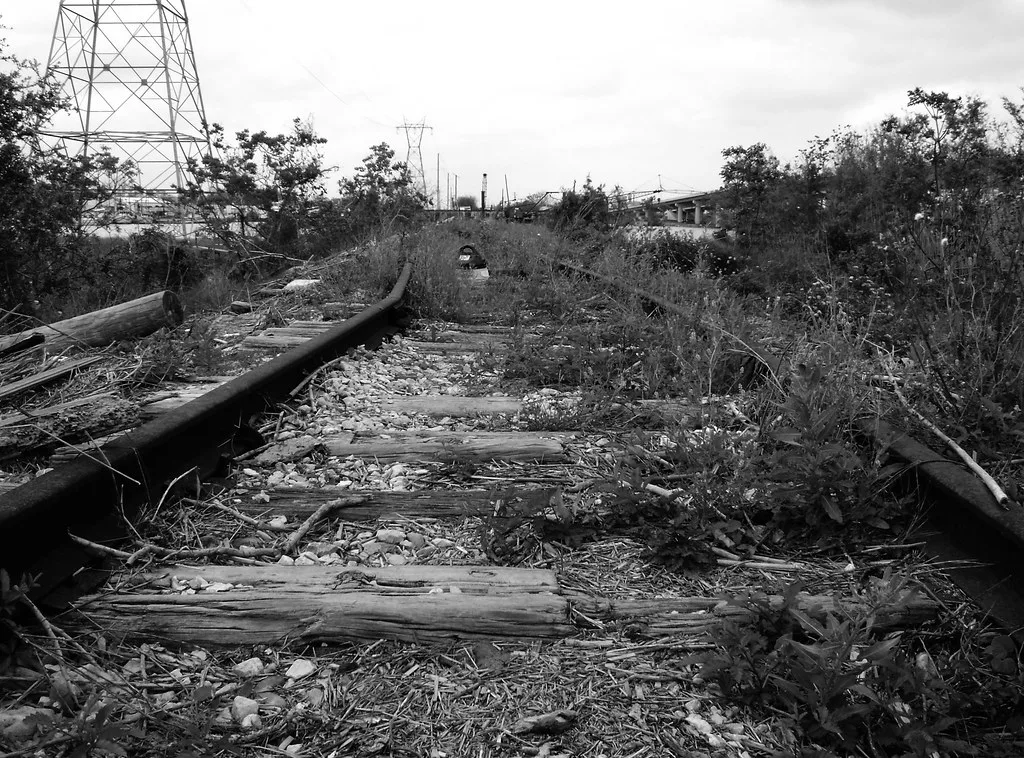 Old railway track with worn sleepers overgrown with vegetation.