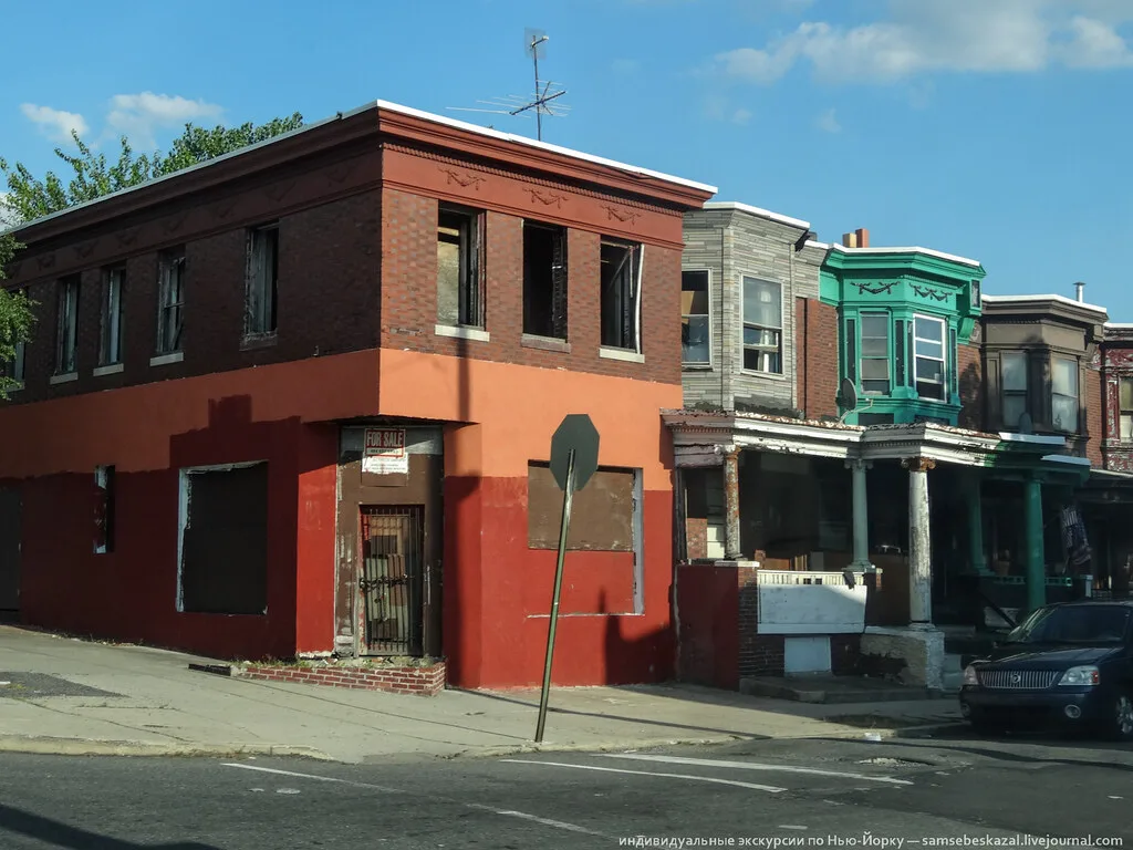 Red and orange brick corner building with empty and boarded windows.