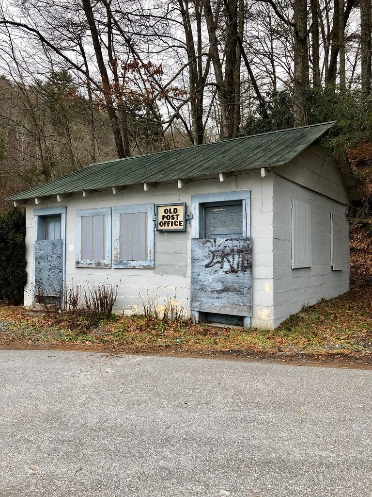 Ancien petit bureau de poste aux portes et fenêtres condamnées.