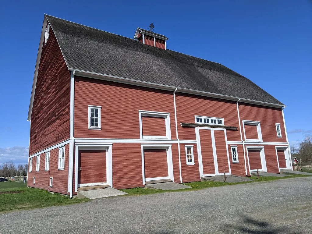Large red barn at Hovander Homestead Park with white-trimmed doors and windows.