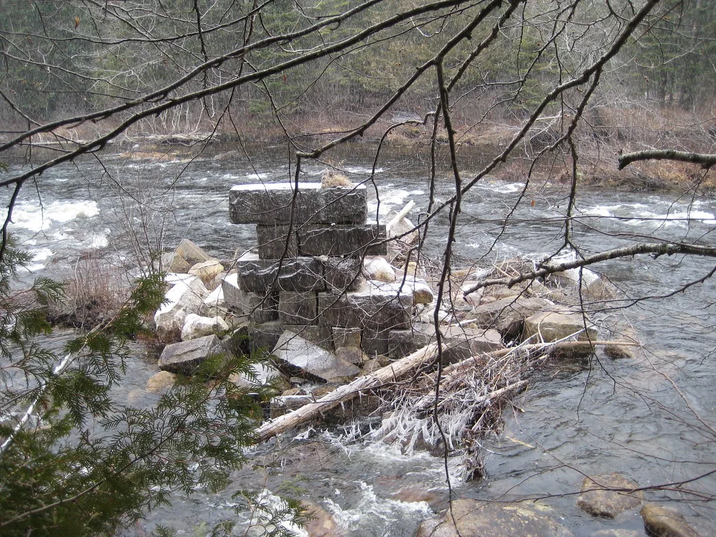 Remains of a stone bridge pier in a river.