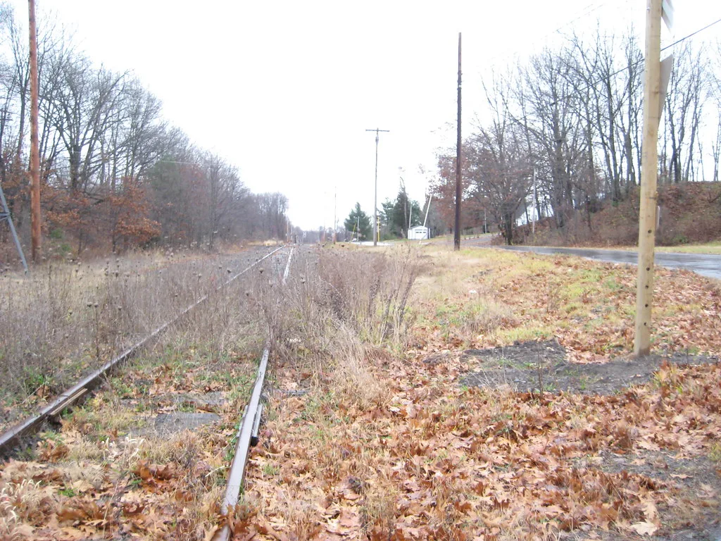 Old railway track overgrown with weeds beside a deteriorated platform.