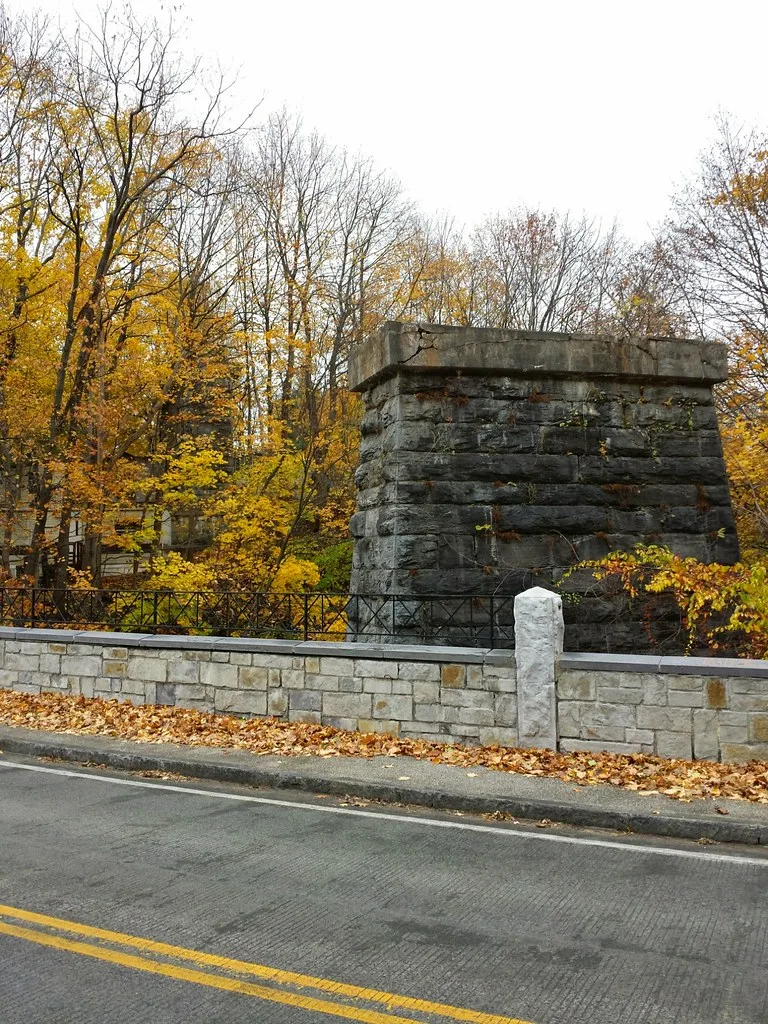 Isolated old stone bridge pier beside a road.