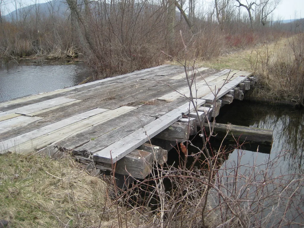 Old deteriorated wooden bridge over a watercourse.